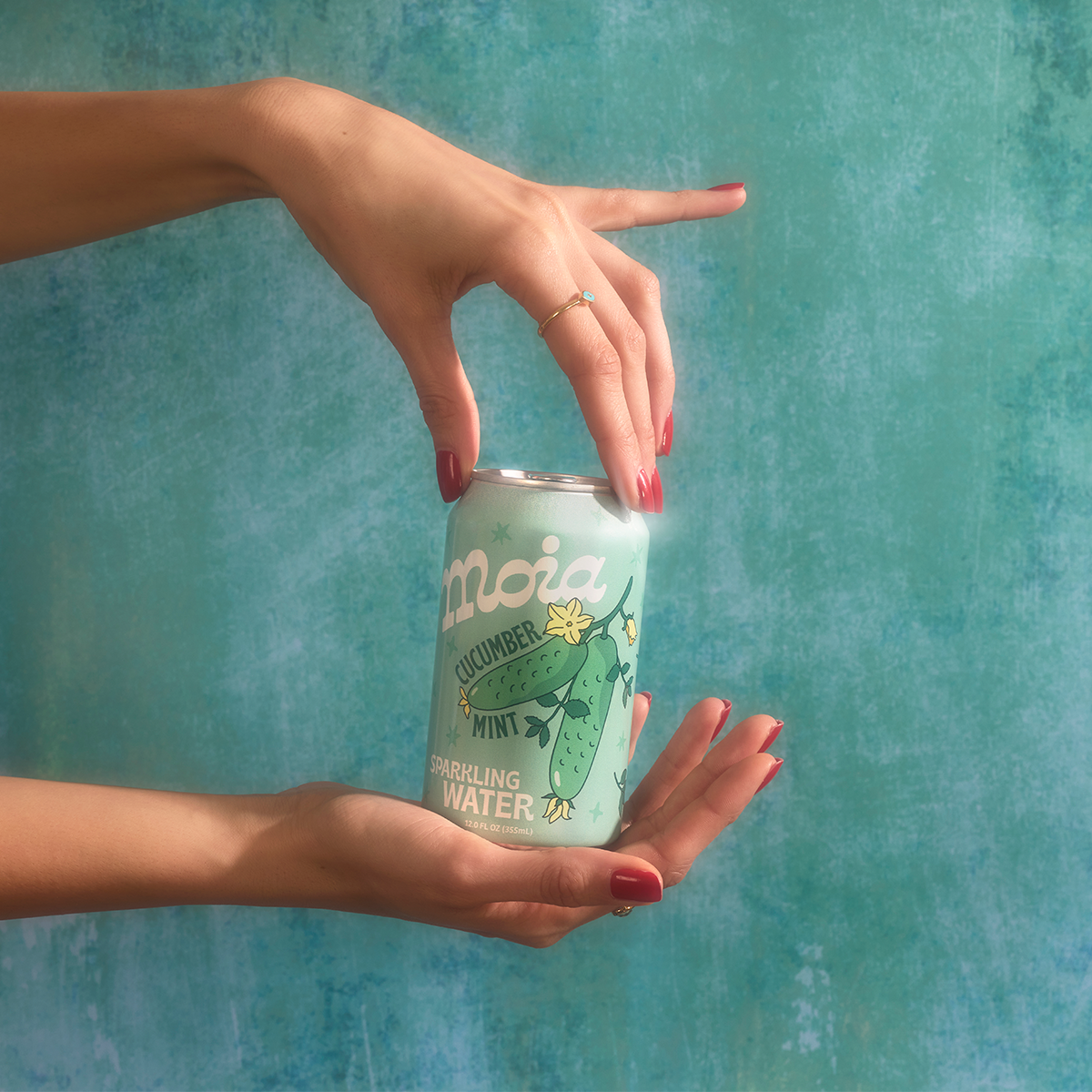 Cucumber mint can being held by nice hands with red nail polish